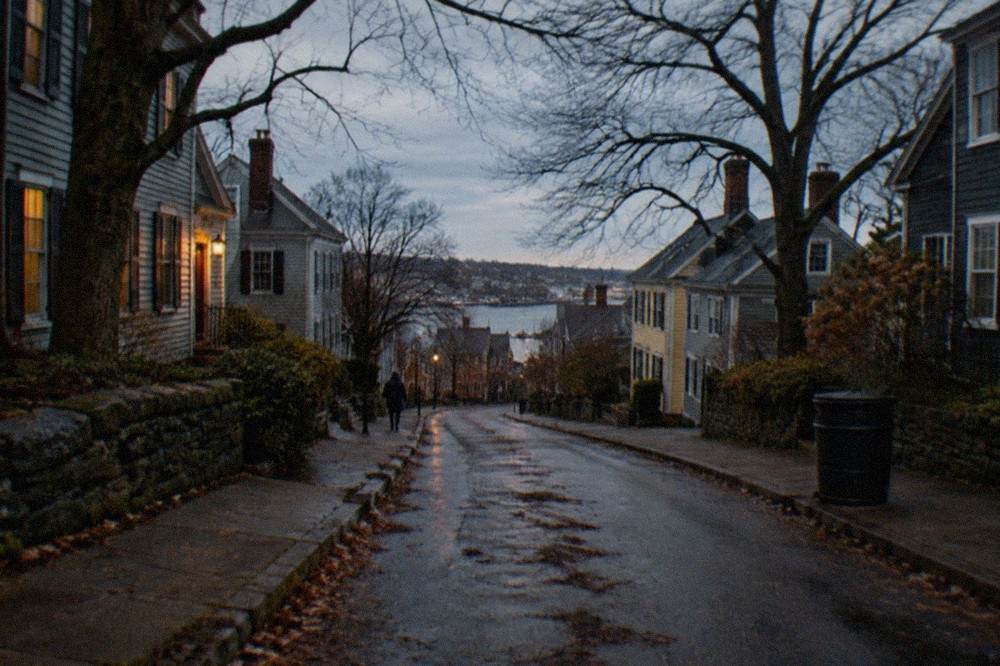 Quiet residential street climbing a hill in Salem at dusk with bare trees
