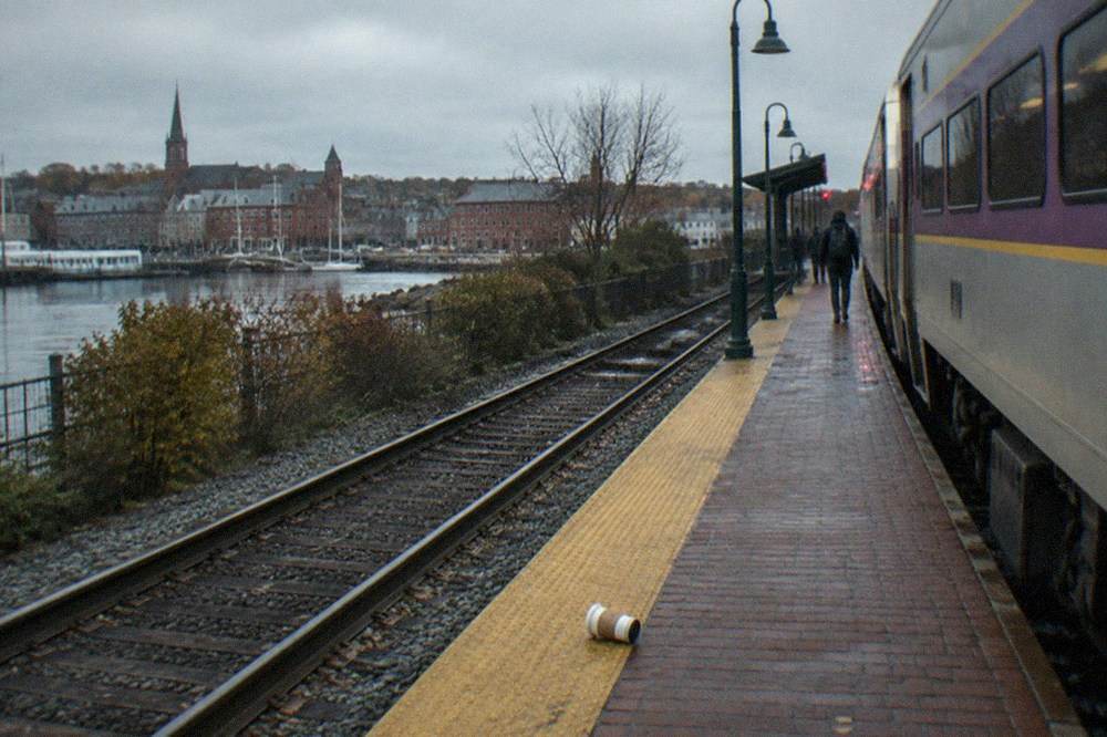 Commuter rail platform with a waiting train under an overcast sky