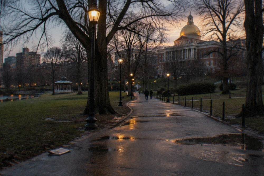 Boston Common at dusk with street lamps glowing along a paved path