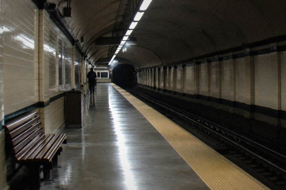 An empty subway station platform with lights reflecting on the tiles