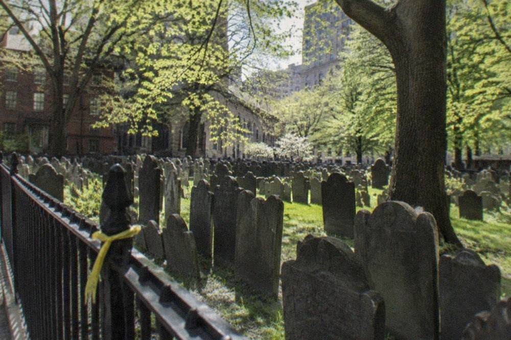 Old slate headstones standing in tight rows inside a colonial Boston burying ground