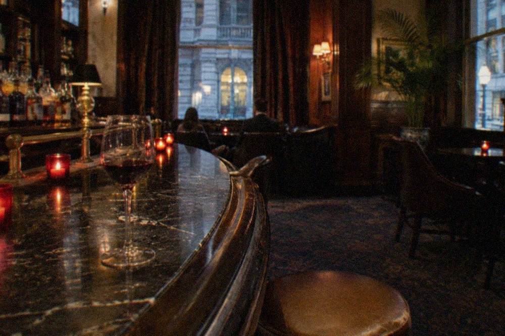 A candle-lit historic tavern interior with a dark wooden bar and brass fittings