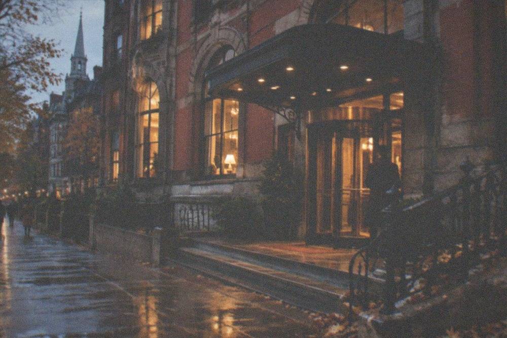 The facade of a grand historic brick hotel on a city street at dusk