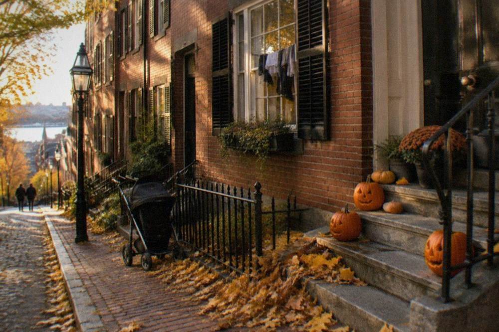 A decorated Beacon Hill street with carved pumpkins and autumn leaves on brick sidewalks