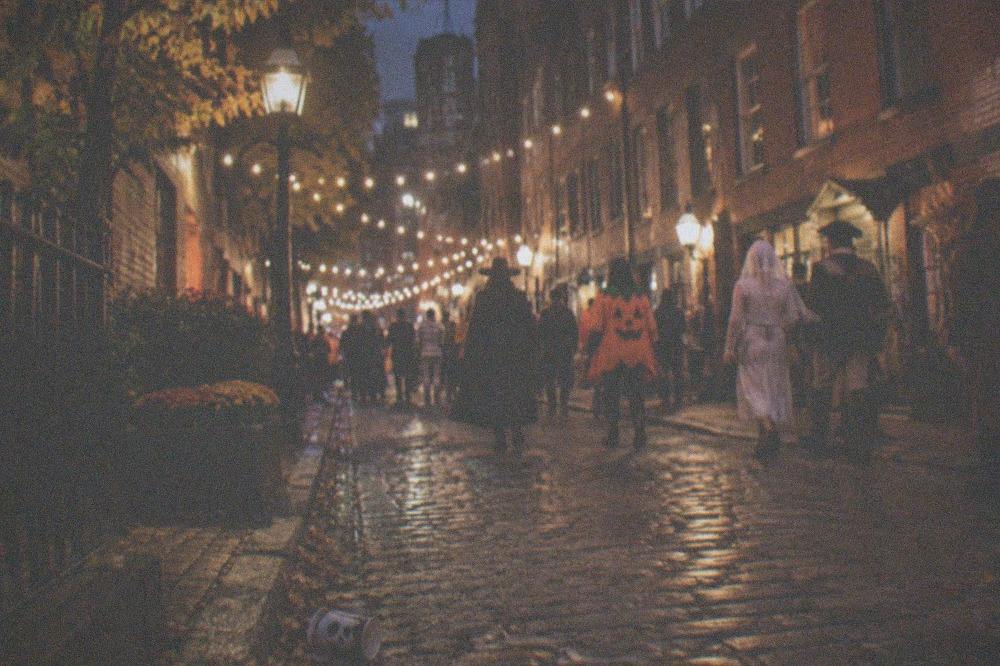 A festive Boston street at night with warm lights and autumn evening crowds