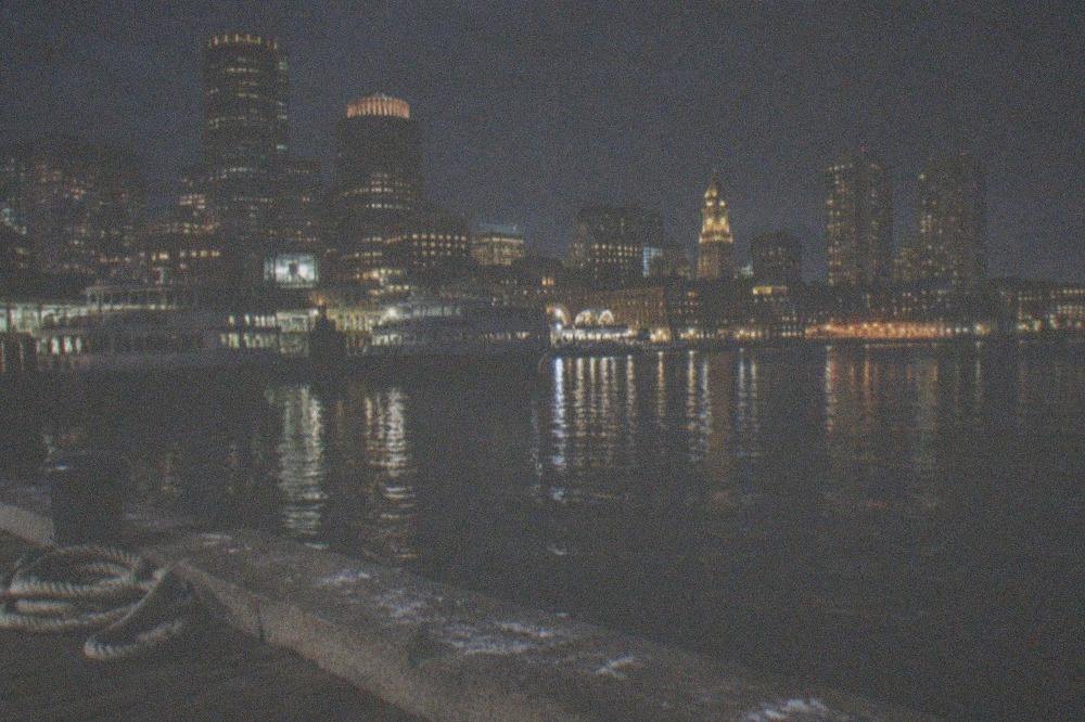 Long Wharf at night with docked ferries and city lights reflecting on the harbor water