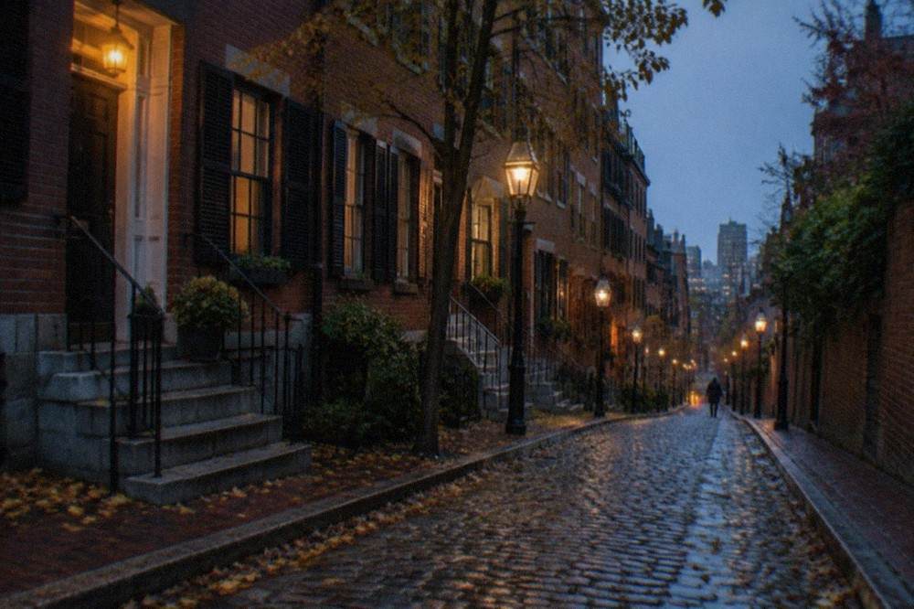 A narrow Beacon Hill street lit by street lamps with brick row houses at dusk