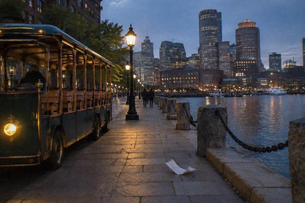 An open-sided sightseeing trolley parked on a Boston waterfront street at night
