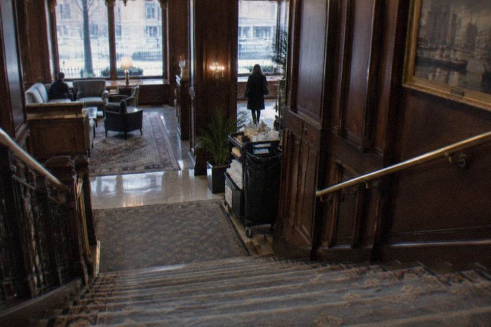 Historic hotel lobby with dark wood paneling, brass fixtures, and a grand staircase