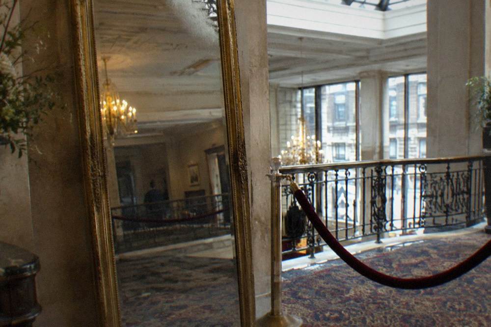 Antique full-length mirror standing in a hotel mezzanine beside a velvet rope